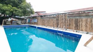 a swimming pool with blue water next to a wooden fence at RedDoorz at DBuilders Rooms Lower Bicutan in Manila