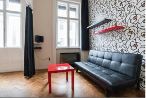 een woonkamer met een zwarte bank en een rode tafel bij SparrOwl Apartments in Boedapest