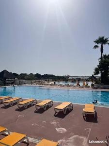 a swimming pool with yellow tables and chairs in it at Mobile Home 168 pour 6 pers Camping Siblu Lac des Rêves Perols in Lattes +15 photos
