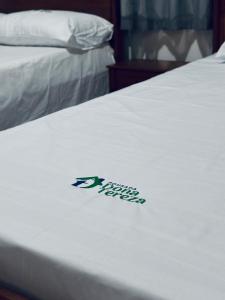 a sticker on a white bed with aigil on it at Pousada Dona Tereza in Mâncio Lima
