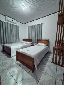 two beds in a room with two windows at Pousada Dona Tereza in Mâncio Lima