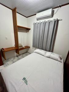 a bedroom with a white bed and a window at Pousada Dona Tereza in Mâncio Lima