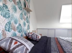 sypialnia z łóżkiem z poduszkami i tropikalną tapetą w obiekcie L'artistique, 4 lits, 2 chambres, stationnement gratuit, spacieux, atypique w Amiens