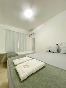 a white room with a bed with two towels on it at Ap da Thay - Os Três Pandeiros in Campina Grande