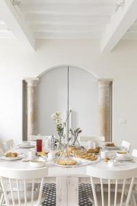 a white dining room with a table with food on it at La Pervinca - Ospitalità, Natura, Cura in Guastalla +38 photos