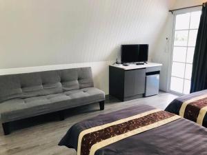 a room with two beds and a couch and a television at ภูเคียงน้ำรีสอร์ต ที่พักริมน้ำวัดเรืองแสงช่องเม็ก in Ban Nong Mek