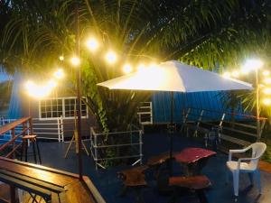 a patio with a table and an umbrella at night at ภูเคียงน้ำรีสอร์ต ที่พักริมน้ำวัดเรืองแสงช่องเม็ก in Ban Nong Mek +1 photo