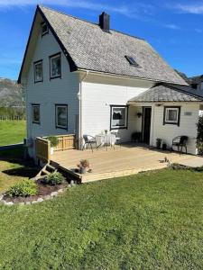 Casa blanca grande con una gran terraza de madera en Oceanview House Ideal for Peaceful Holidays, en Venøya