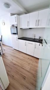 アンベルク・ブッフホルツにあるFerienwohnung in der Altstadt,4 Zentrumの白いキャビネットと木製の床を備えたキッチン +1枚の写真