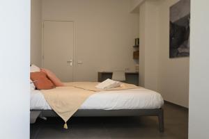 a bedroom with a bed with white sheets and orange pillows at Villa Mer, Bardot - Luxury apartment in Badhuis with swimming pool and sauna near the beach in Cadzand +52 photos