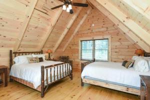 2 letti in una camera da letto in una baita di tronchi con soffitto di Stone Lake Lodge - Lakeside Cabin - Stocked Pond a Coshocton Altre 30 foto