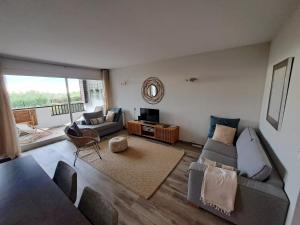 uma sala de estar com um sofá e uma TV em Superbe appartement piscine, tennis, vue mer et décoré avec goût em Cassis