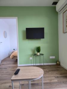 ストラスブールにある303 - Strasbourg appartement Green refait à neufのテーブルと壁にテレビが置かれたリビングルーム