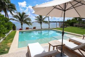 a swimming pool with an umbrella and chairs at Villa Azanik in Tulum