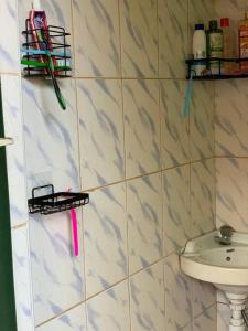 a white tiled bathroom with a sink and a toilet at Charming Double House in Jinja in Jinja