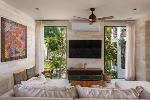 a living room with a couch and a flat screen tv at Villa Azanik in Tulum