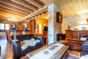 a living room with a leather couch and a stone fireplace at Chalet Alpin 12 pers, Isola 2000 in Isola 2000