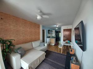 a living room with a white couch and a brick wall at Segurança e conforto na Praia Brava a 100 do mar - Condomínio Curimã in Florianópolis