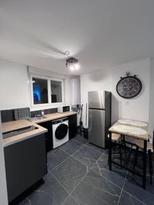 a kitchen with a stainless steel refrigerator and a table at Espace Chic et Cosy in Dunkerque