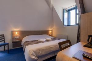a hotel room with a bed and a desk and a table at Auberge de la Loire in Montjean-sur-Loire
