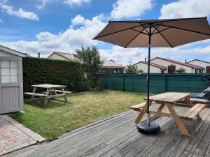 a picnic table and an umbrella on a deck at Zalig genieten van de zeelucht! in De Haan
