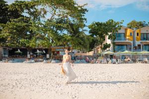 沙美岛Diamond Beach Resort的穿白色衣服的女人在海滩上散步