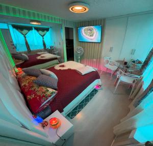 1 dormitorio con 2 camas, mesa y TV en Gold House Oro, en Quito