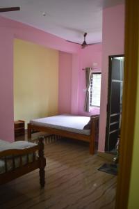 Un dormitorio con dos camas en una habitación con paredes rosas. en Shivanugraha Homestay, en Gokarna