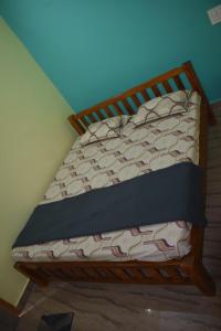 una cama vacía en una habitación con una pared azul en Shivanugraha Homestay, en Gokarna