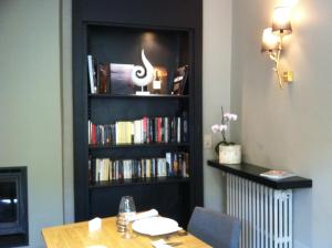 une étagère remplie de livres à côté d'une table dans l'établissement Hôtel Le Cobh, à Ploërmel
