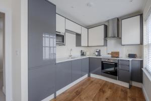 チェルムスフォードにあるModern 2 bed town house quiet street near stationのキッチン(グレーのキャビネット、白い電化製品付)