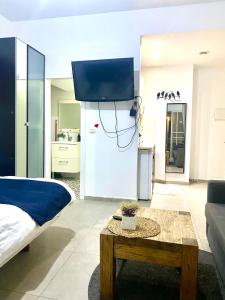 a living room with a bed and a tv on a wall at כמו חדר במלון מרפסת חניה פרטית in Tel Aviv