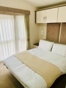 a bedroom with a large white bed and a window at Lakeside mini lodge in Saint Osyth