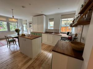 a kitchen with white cabinets and a wooden floor at 2 bed luxe garden apartment in London