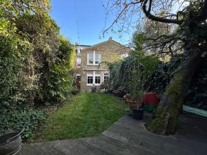 a backyard of a house with a yard with plants at 2 bed luxe garden apartment in London