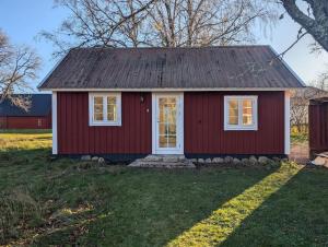 a small red house with a white door at Kleines modernes Haus in Borghamn in Borghamn