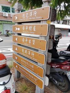 a group of signs on a pole next to motorcycles at Chongguang Hotel in Tainan