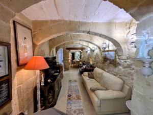 a living room with a couch in a stone wall at Traditional Maltese House in centre of Town in Mosta