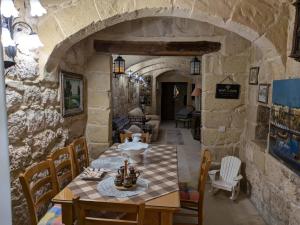 a dining room with a table and a stone wall at Traditional Maltese House in centre of Town in Mosta