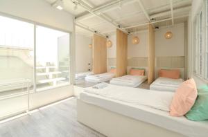 a bedroom with three beds and a large window at The Locals Bangkok Old Town in Bangkok