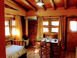 a bedroom with a table and a bed and windows at Cabañas Calderón I in San Rafael