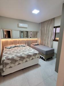 ein Schlafzimmer mit zwei Betten und einem Spiegel in der Unterkunft Apartamento novo luxo, 2 suítes, piscina aquecida no condomínio, 1 quadra do mar, completo in Bombinhas