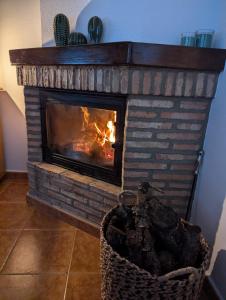 a brick fireplace with a fire in it at Casa Corredera in Cumbres Mayores
