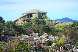 an old building on top of a hill with flowers at Hospedaria Oliveira - São Thomé das Letras in São Thomé das Letras