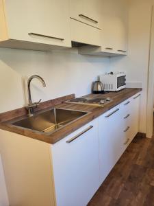 a kitchen with white cabinets and a sink at Appartamento San Bartolomeo in Passo del Tonale