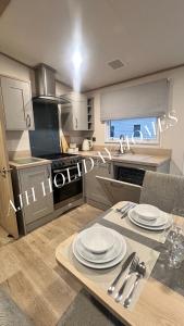 eine Küche mit einem Tisch mit Tellern darauf in der Unterkunft AJH Holiday Homes, Ty Mawr- Parkdeans Resort in Kinmel Bay