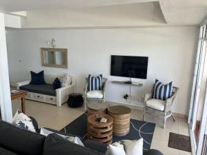 a living room with a couch and a flat screen tv at Palm Cove - 52 Chakas Cove, Penthouse-Literally on the Beach in Ballito