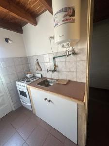 a small kitchen with a sink and a microwave at Alvear Centro Hospedaje in General Alvear