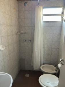 a bathroom with a toilet and a sink and a shower at Alvear Centro Hospedaje in General Alvear +2 photos