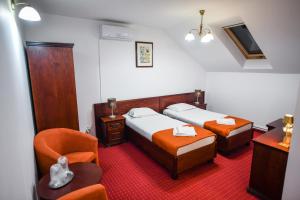 a hotel room with two beds and a chair at Hotel Elyon Dej in Dej